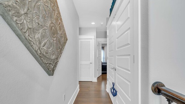 Um corredor com uma porta branca, um sino azul e um objeto decorativo na parede.