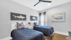 Quarto com duas camas, ventoinha no teto e decoração temática náutica.