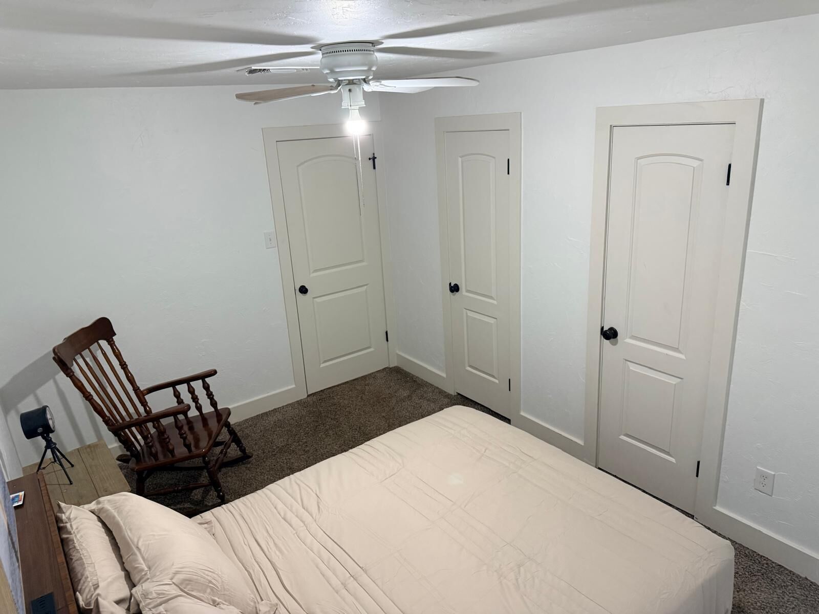 A bedroom with a bed, a chair, and two doors.