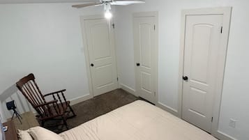 A bedroom with a bed, a chair, and two doors.