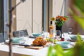 A table set for dining with a loaf of bread, a bottle of wine, and a vase of flowers. - Le Cappatti, 2 bedroom apartment (Nice)