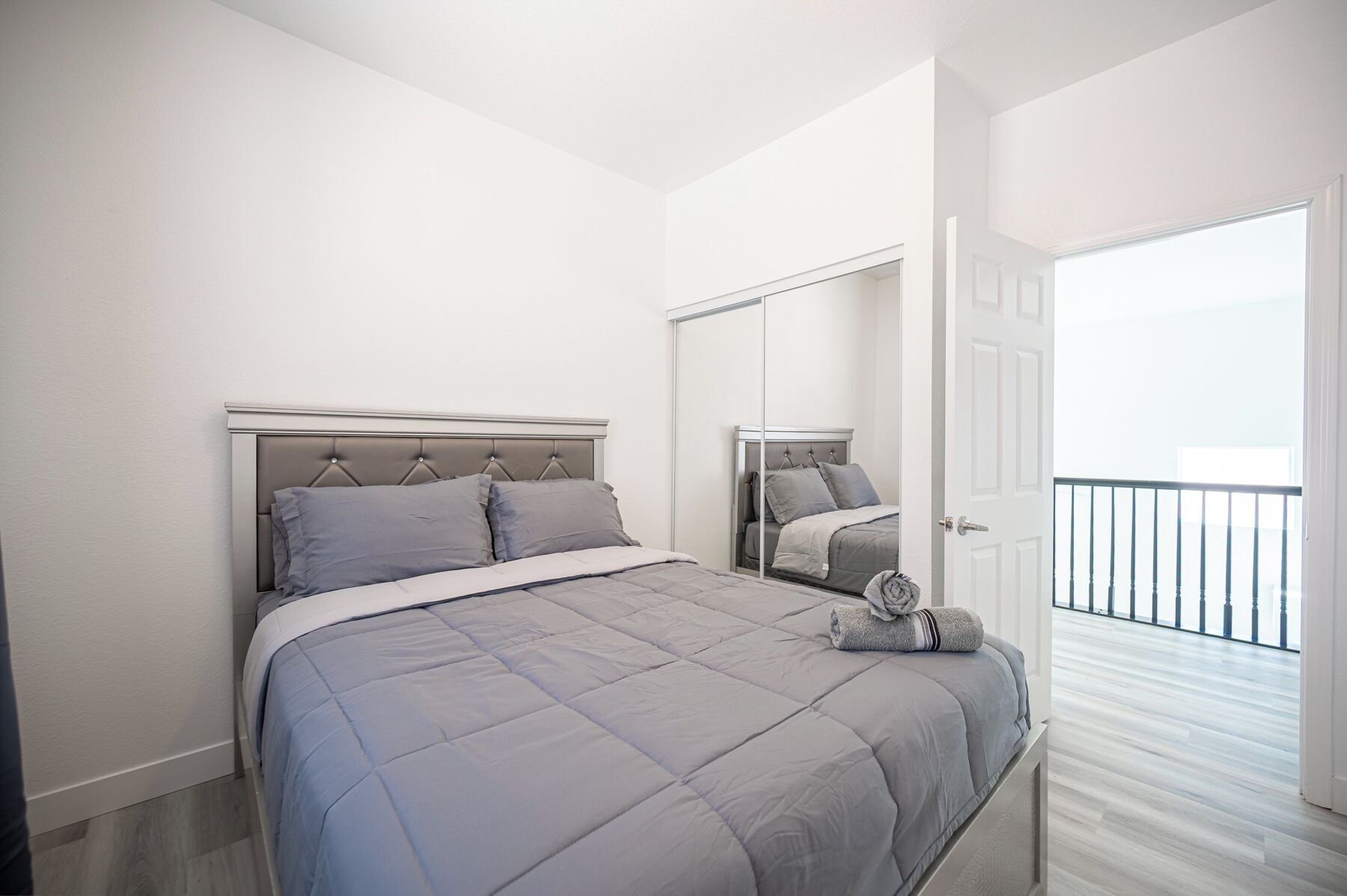 Un dormitorio con cama, un espejo y vistas a un balcón.