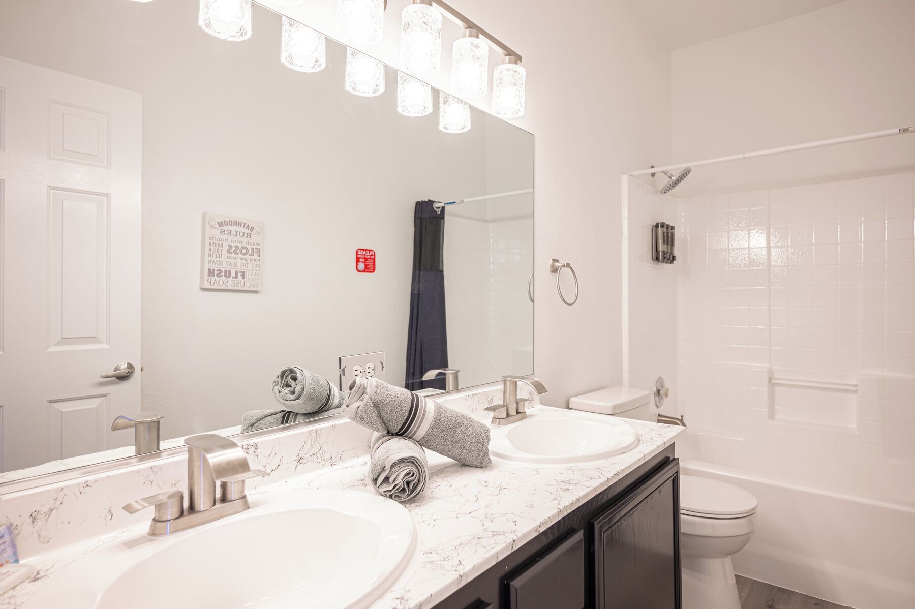 A bathroom with two sinks, a mirror, and a shower.