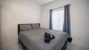 A bedroom with a bed, a window with curtains, and a wall socket. - Gorgeous 5-bedroom house with Pool in North Las Vegas (North Las Vegas)