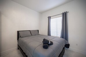 A bedroom with a bed, a window with curtains, and a wall socket. - Gorgeous 5-bedroom house with Pool in North Las Vegas (North Las Vegas)
