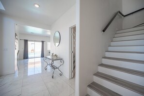 Ein geräumiger Flur mit Marmorboden, einem Glastischchen und einer Treppe mit Holzwegen.