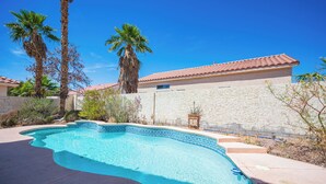 A swimming pool with a tiled edge, surrounded by palm trees and a stone wall. - Gorgeous 5-bedroom house with Pool in North Las Vegas (North Las Vegas)