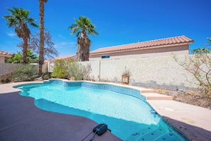 A swimming pool with a tiled edge, surrounded by palm trees and a stone wall. - Gorgeous 5-bedroom house with Pool in North Las Vegas (North Las Vegas)