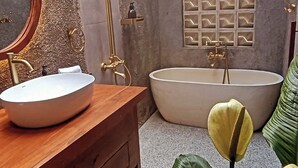 A bathroom with a wooden vanity, a white sink, a freestanding bathtub, and a wall-mounted shower. - Cozy 1-bedroom hotel suite in enchanting Ubud
with AC (Gianyar)