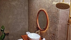 A bathroom with a wooden vanity, a white sink, a mirror, a showerhead, and a toilet. - Cozy 1-bedroom hotel suite in enchanting Ubud
with AC (Gianyar)