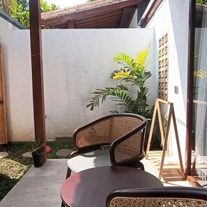 Ein Patio mit Stuhl, kleinem Tisch und einem Blumentopf.