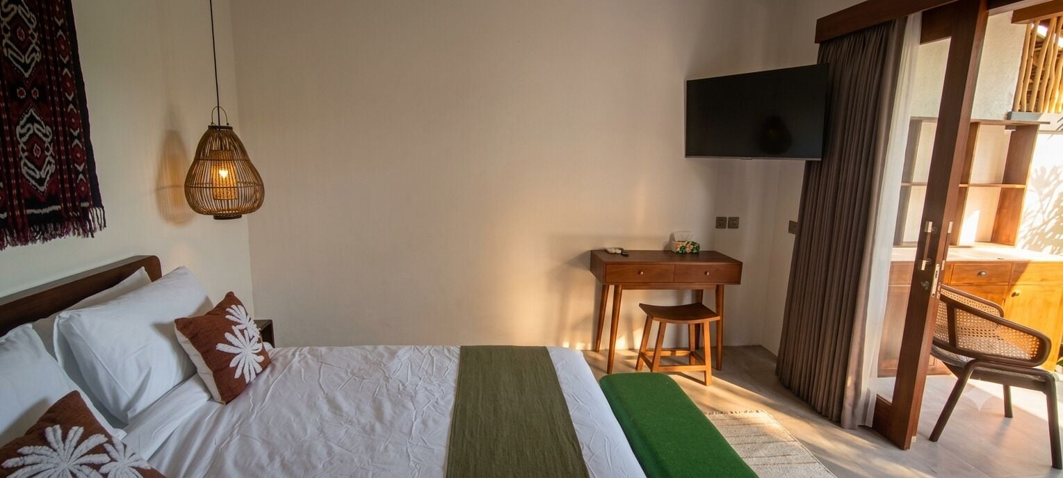 A hotel room with a bed, a desk, a chair, and a television.
