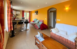 A living room with a sofa, a coffee table, and a dining area with a table and chairs. - Lovely home in Châteauneuf-Villevieil (Châteauneuf-Villevieil)