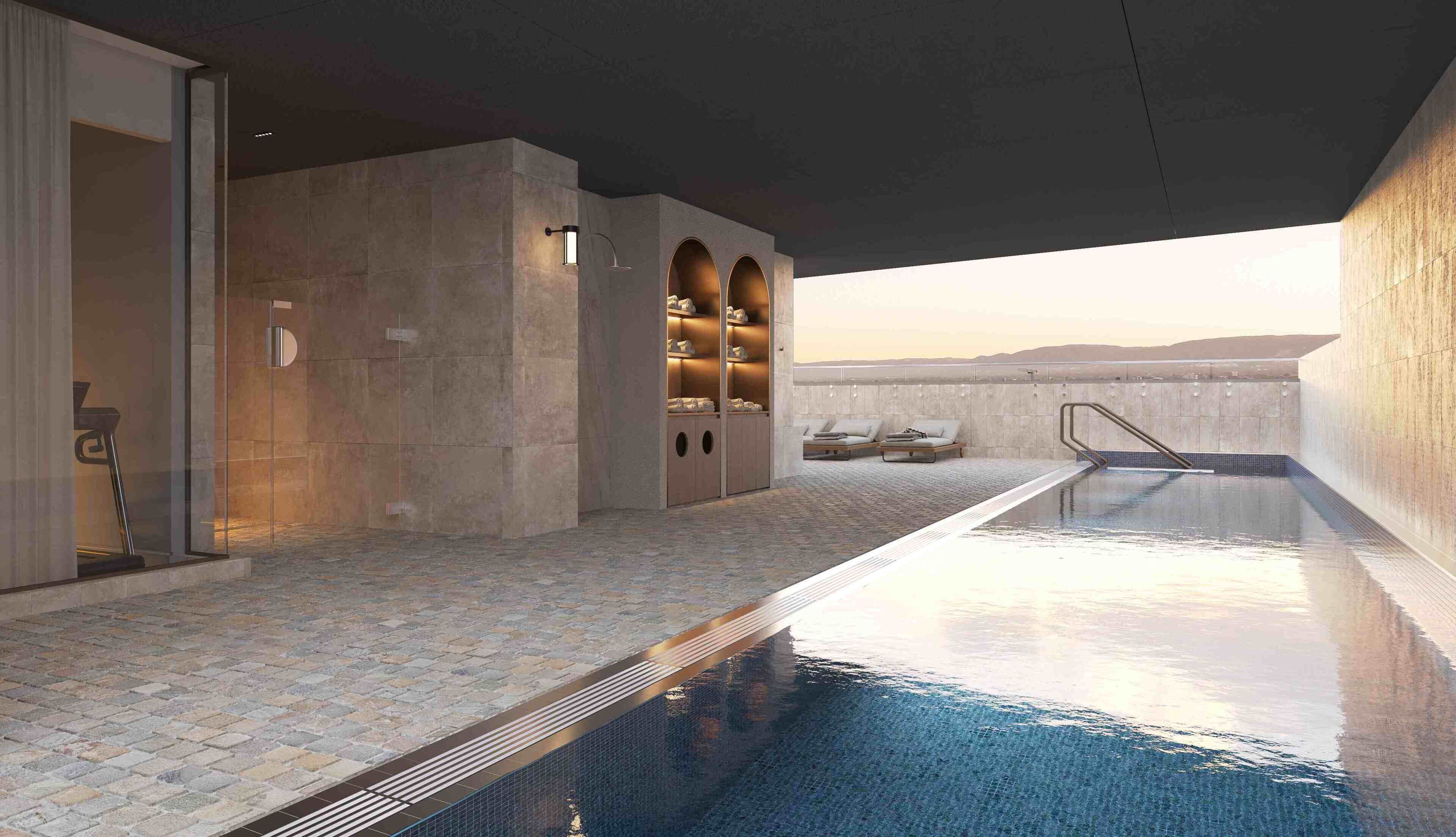 A modern indoor pool area with a clear view of the mountains in the background, a seating area with a lounge chair, and a built-in storage unit with shelves.