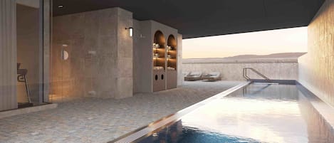 A modern indoor pool area with a clear view of the mountains in the background, a seating area with a lounge chair, and a built-in storage unit with shelves.