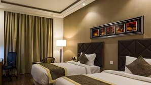 Une chambre d’hôtel avec deux lits, un bureau, une chaise et une lampe.