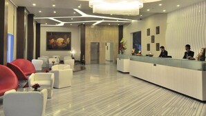 Un hall d’hôtel comprenant un comptoir d’accueil, un espace salon et un grand lustre.