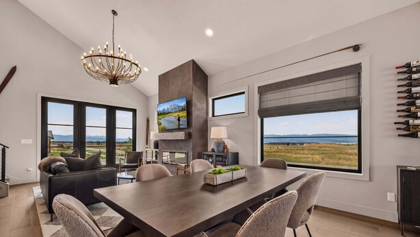 A modern dining area with a large table, chairs, and a chandelier. - Teton Sunset 3BR luxury home sleeps 12 with private hot tub & unbeatable Teton mtn views. (Driggs)