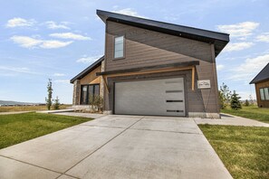 A modern two-story house with a garage, a stone foundation, and a clear sky. - Teton Sunset 3BR luxury home sleeps 12 with private hot tub & unbeatable Teton mtn views. (Driggs)