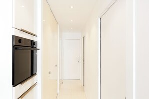 A modern kitchen with built-in appliances and a white door at the end of a narrow hallway. - Upstays Elegant Gray d'Albion 2min Palais (Cannes)
