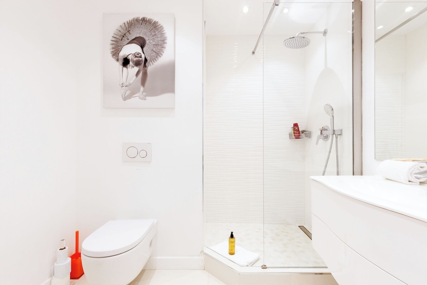 A modern bathroom with a toilet, shower, and sink.