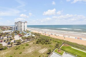 A coastal hotel with a beach view, parking area, and a pool. - New listing! Updated oceanfront 2/2 with private balcony, heated pool, and garage parking (Ormond Beach)