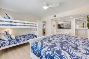 Ein Schlafzimmer mit Etagenbetten, Deckenventilator, Kommode und einem Bild an der Wand.