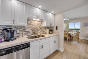 A modern kitchen with white cabinets, a coffee machine, and a dishwasher. - New listing! Updated oceanfront 2/2 with private balcony, heated pool, and garage parking (Ormond Beach)