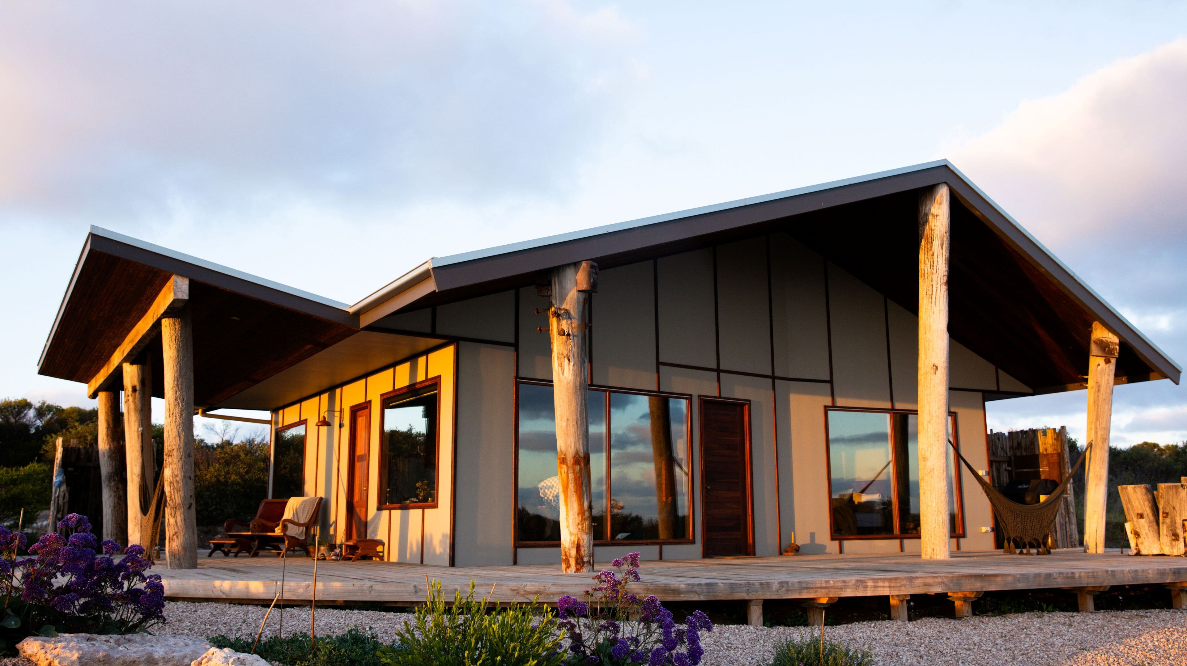 A modern house with a covered porch, large windows, and a wooden deck.