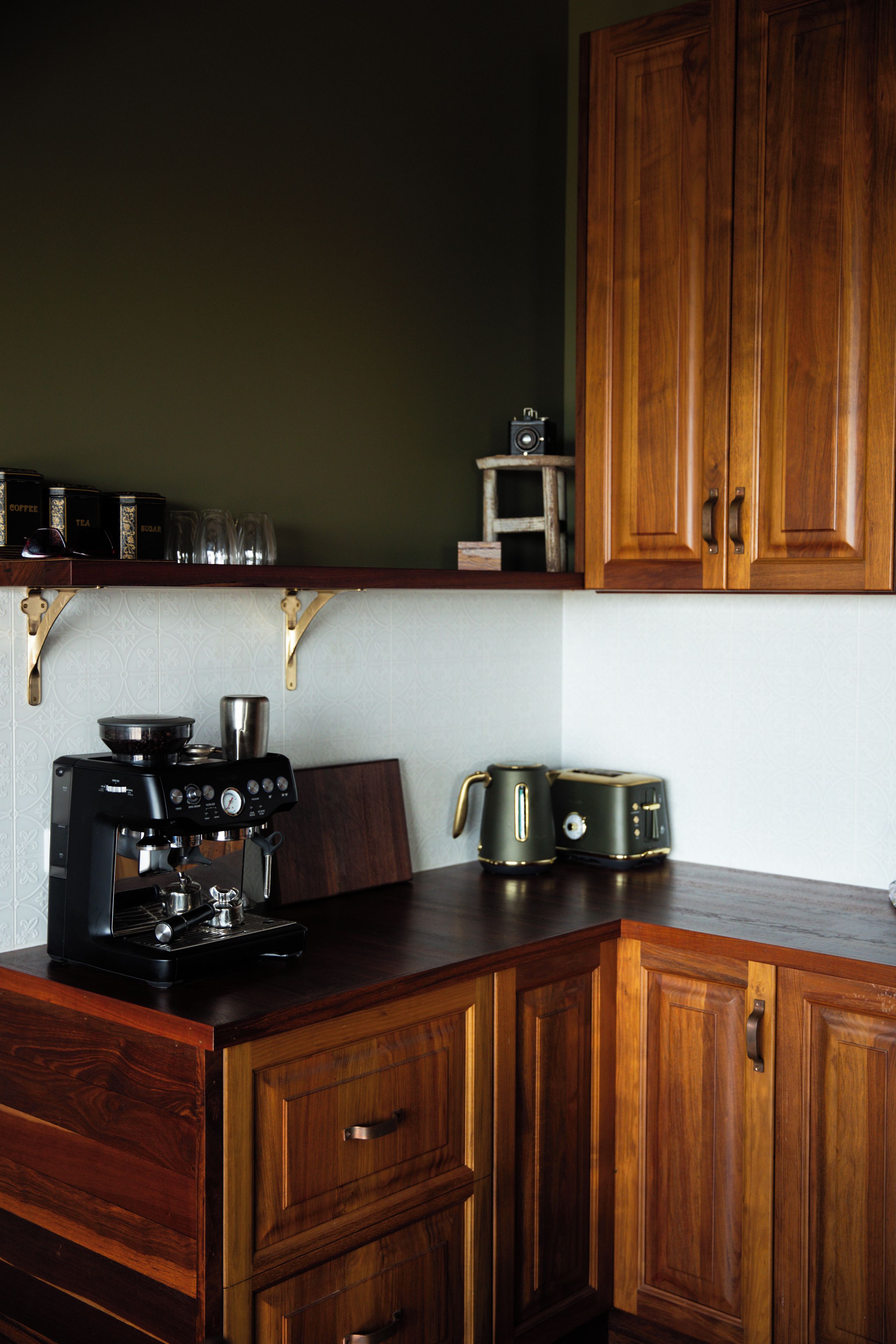 Una cocina con armarios de madera, cafetera, hervidor y tostadora.