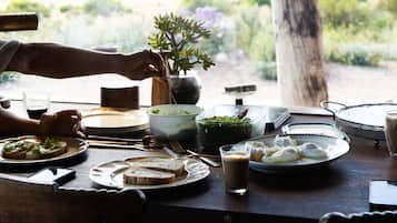 A dining table with various dishes, a cup of coffee, and a view of the outdoors.