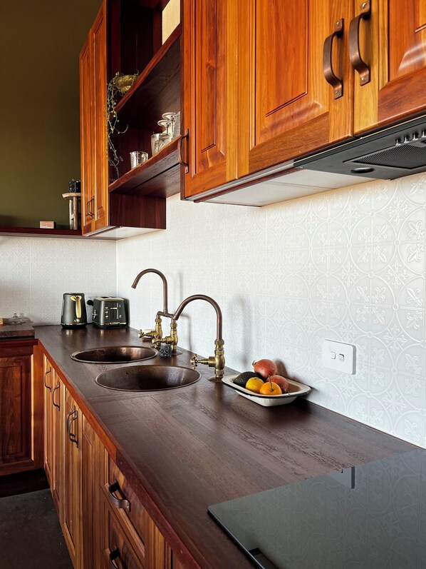 A kitchen with wooden cabinets, a double sink, and a fruit bowl on the counter.