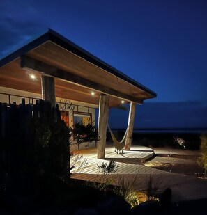 Une maison moderne dotée d’un porche abrité, de poutres en bois et d’un hamac.