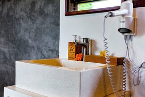 Ein Badezimmer mit einem großen, rechteckigen Waschbecken, einer Handbrause und einem an der Wand befestigten Föhn.
