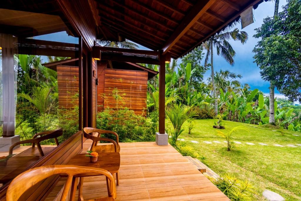 A wooden deck with a bench and chairs, surrounded by lush greenery and palm trees.