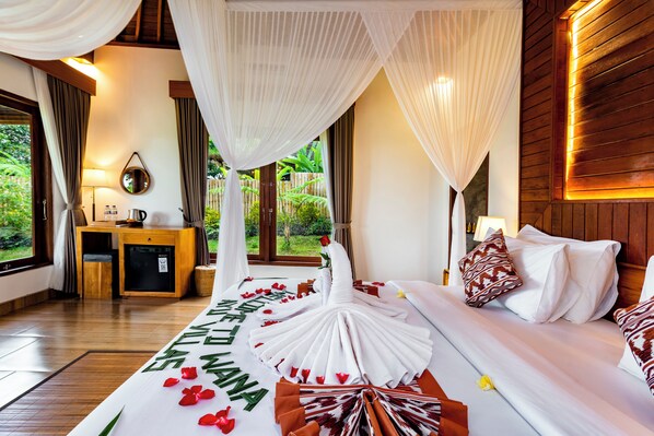 Un dormitorio con cama con dosel, una mesita de noche, una lámpara y vistas al exterior con vegetación.