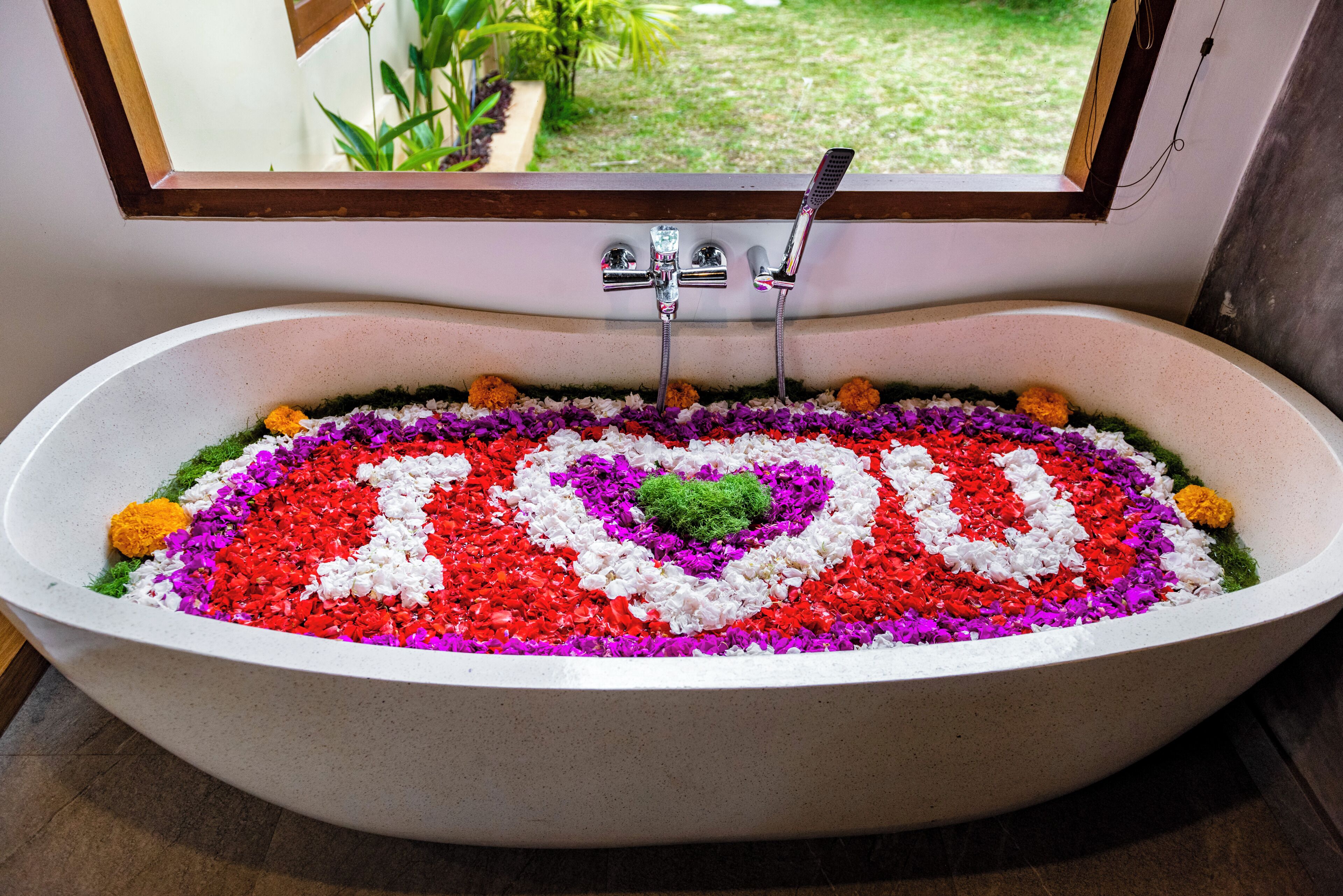 Una bañera con una decoración floral que deletrea 'YOU' en el agua.
