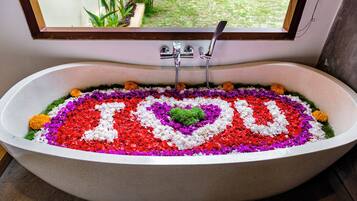 Una bañera con una decoración floral que deletrea 'YOU' en el agua.
