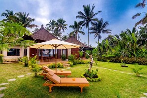 Un resort tropical con zona de piscina, sillas de descanso y una zona de estar cubierta.