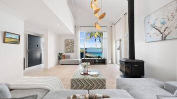 A modern living room with a fireplace, a sofa, a coffee table, and a view of the sea.