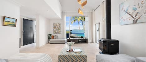 Una sala de estar moderna con chimenea, un sofá, una mesa de centro y vistas al mar.