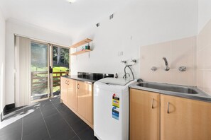 Una cocina moderna con lavadora incorporada, un lavamanos y una puerta corrediza de vidrio que da a un balcón.