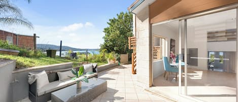 Patio esterno moderno con area salotto, una porta vetrata che dà su una stanza e vista sul mare.