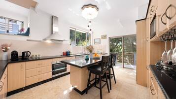 A modern kitchen with a large island, built-in appliances, and a view to the outside.