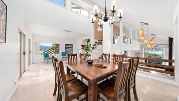Un'ampia sala da pranzo con tavolo e sedie in legno, un lampadario e vista sull'esterno.
