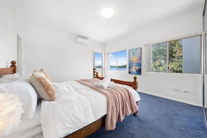 Un dormitorio con una cama grande, una ventana con vistas a un paisaje y un cuadro en la pared.