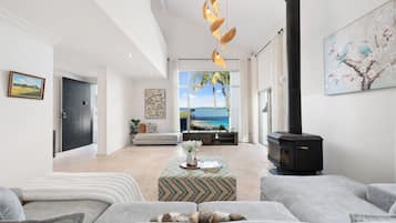 A modern living room with a fireplace, a sofa, a coffee table, and a view of the sea.
