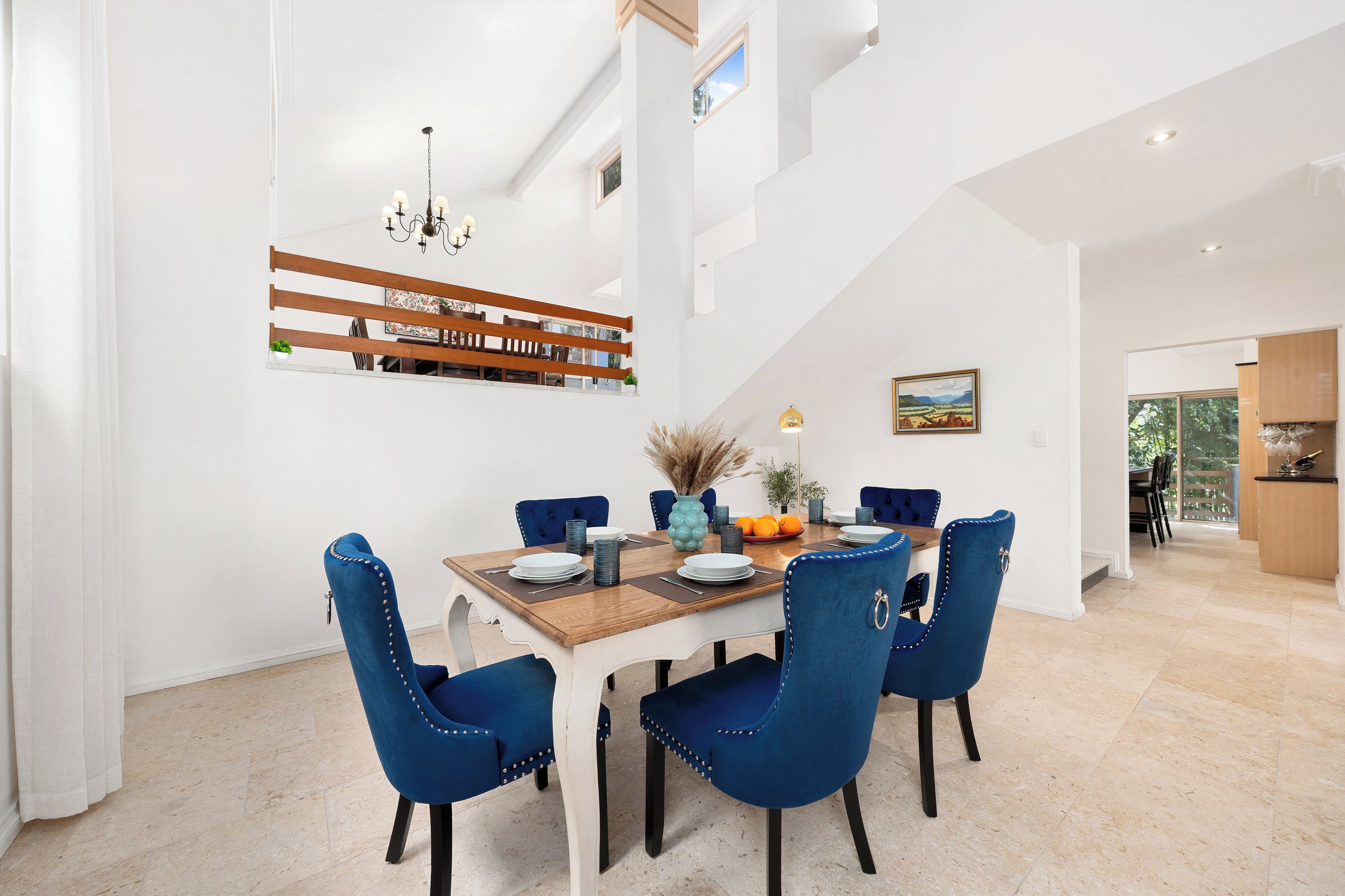 A dining area with a wooden table, blue upholstered chairs, and a chandelier.