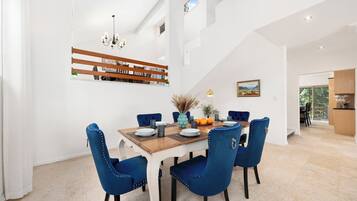 A dining area with a wooden table, blue upholstered chairs, and a chandelier.