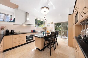 A modern kitchen with a large island, built-in appliances, and a view to the outside.